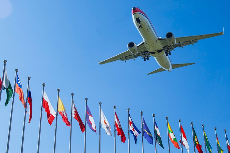 A plane flying over a range of international flags