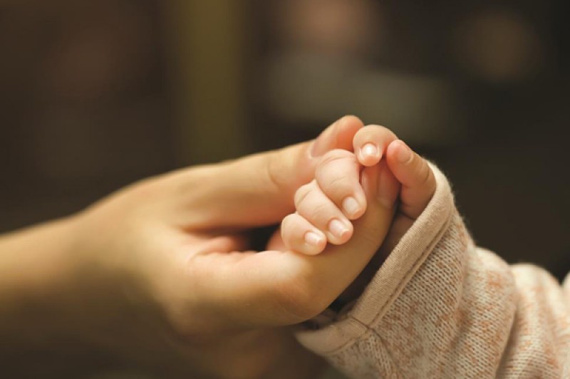 Mother holding hand of baby